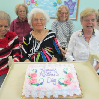 Senior ladies sitting by the tray with birthday cake